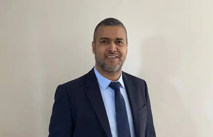 Homme d'affaires en costume élégant pour réseau professionnel, visage souriant, fond neutre blanc.