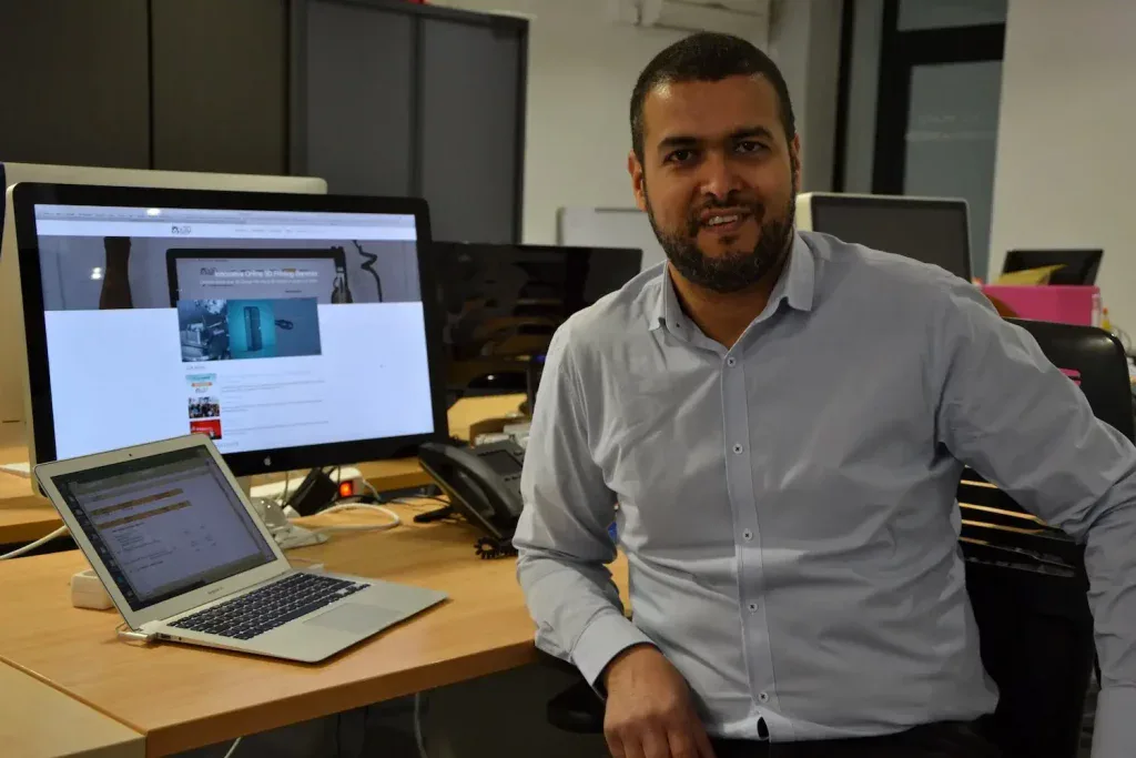 Capture d'écran d'un professionnel travaillant sur un ordinateur avec affichage 3D, dans un bureau moderne.